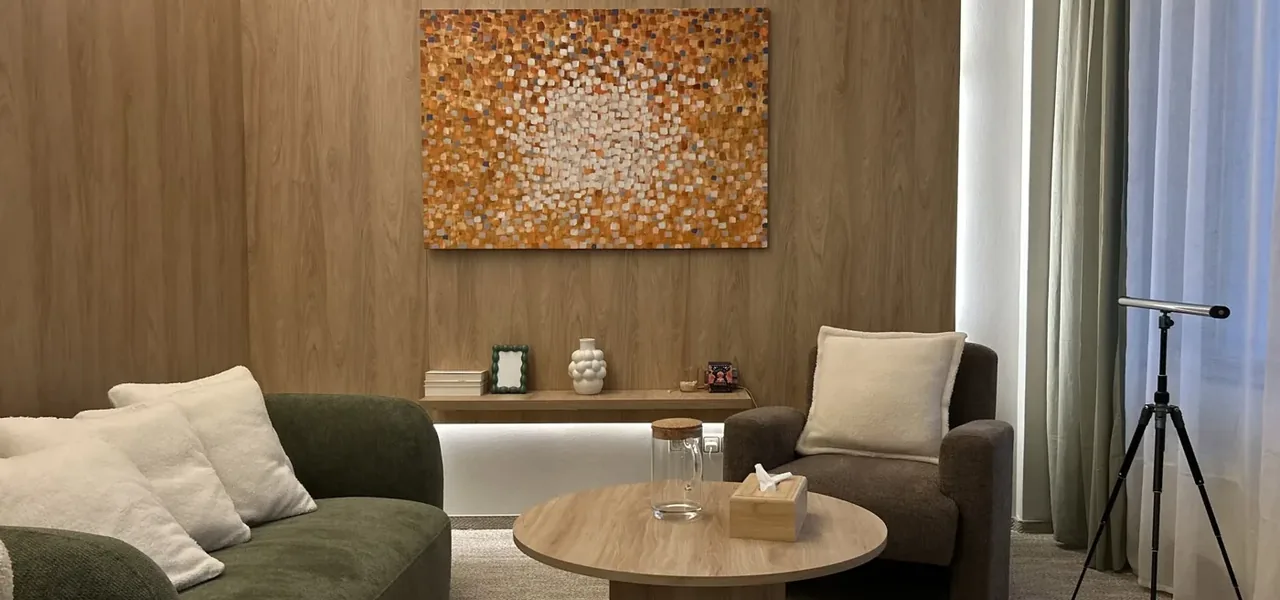 Gabinet VITA 72 — zielona sofa, fotel i okrągły stolik w ciepłym świetle
